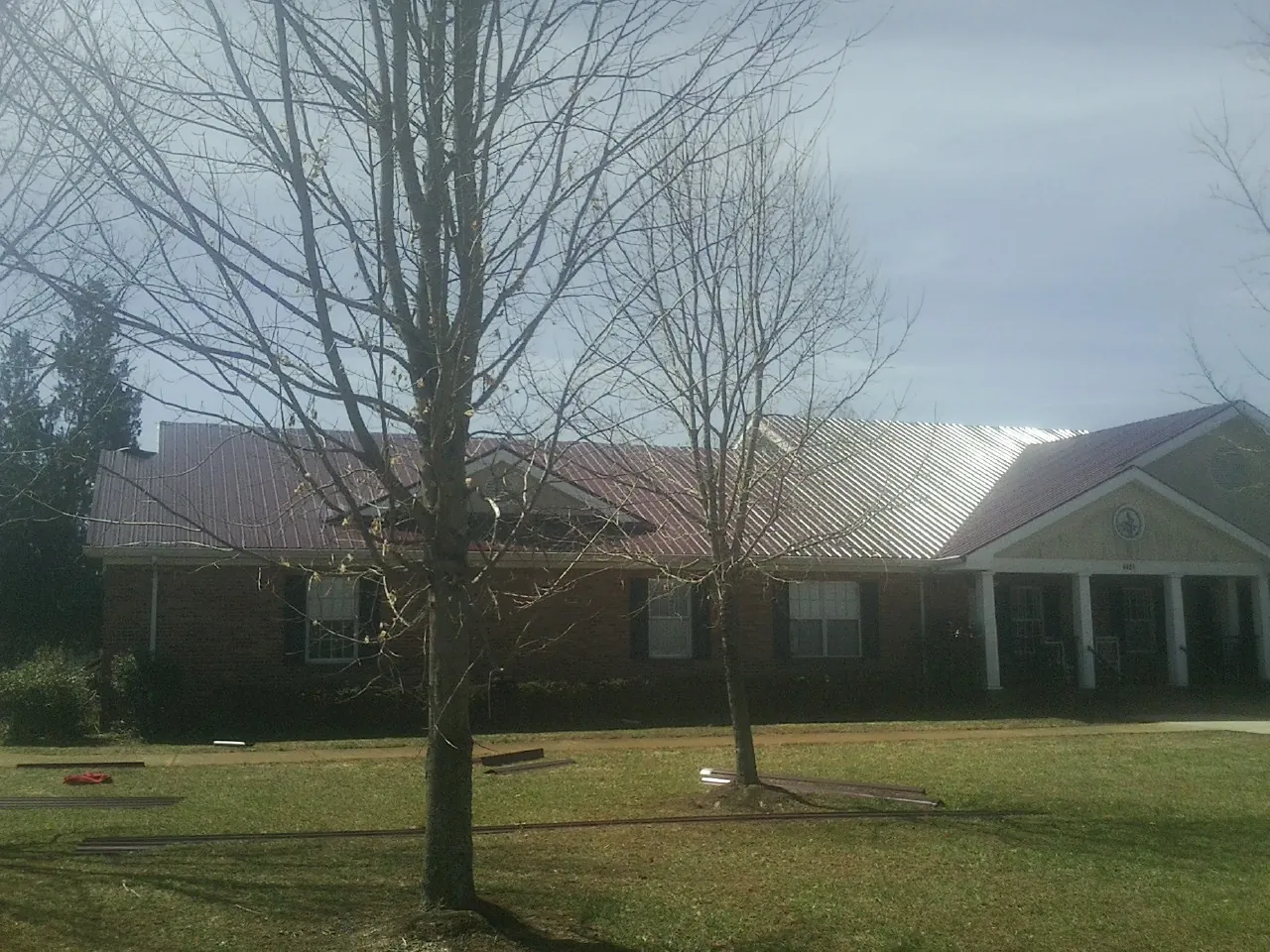 Red metal roof on a brick building seen from the front lawn in Claxton