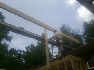Carpenter setting a ridge beam over a new addition frame — Ice Dam Removal by Roofing Brothers in Claxton