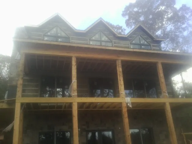 Dormers and porch framing on a large log home under construction — Roof Coating work by our crew in Claxton