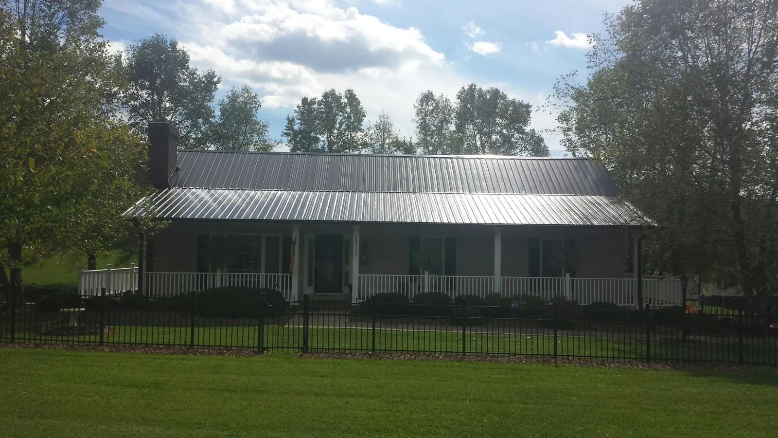 Gray metal roof on a brick ranch with a full width front porch — Gutter Guard Installation work by our crew in Claxton